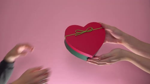 Hands Exchange Heart Shaped Gift on Pink Background