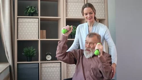 Woman Helps Senior Man Lift Dumbbells