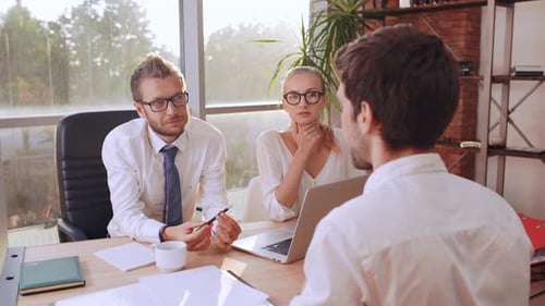 Young Caucasian Businessmanin White Shirt Explaining Something to Boss and Female Secretary While