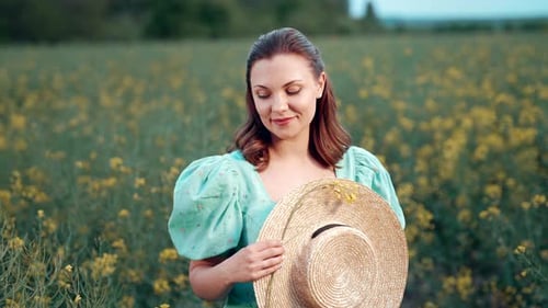 Porträt einer attraktiven Frau, die im Feld der blühenden Rapsblumen posiert