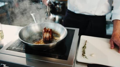 Close-up of a filet mignon being cooked in a frying pan