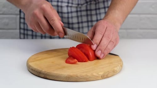 Slicing a Ripe Tomato on a Wooden Board