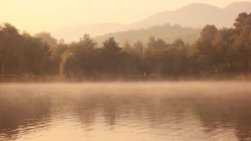 Nebliger Morgen auf einem See bei Sonnenaufgang.
