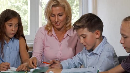 Teacher Helping Students With Schoolwork in Classroom