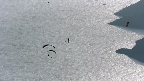 Gleitschirmflieger fliegen mit Gleitschirmfliegen im Himmel über Wald, Berggipfel und Meer