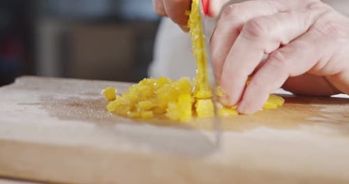 Slow motion close up of a chef knife slicing a yellow bell pepper