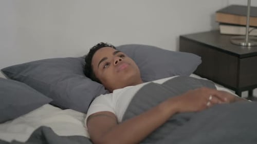 Femme africaine éveillée au lit en pensant