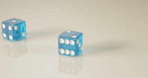 Macro disparo a cámara lenta de dados cayendo y rodando sobre una superficie reflectante