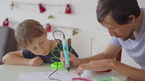 Close Up shot of a little boy that is using a 3d pen