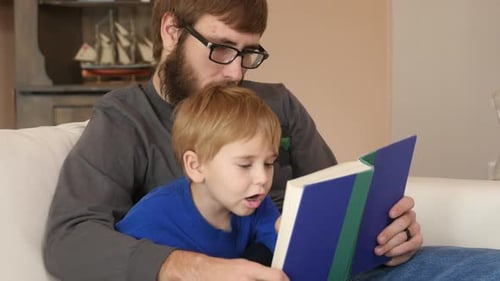 Father and Son Read Book Together Indoors