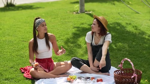 Two Women Having Picnic Together Sitting on the Plaid on the Park Lawn