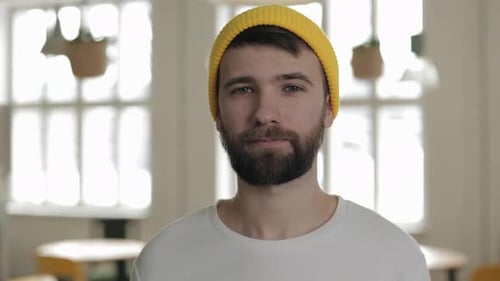 Homem caucasiano bonito com chapéu amarelo moderno posando no café