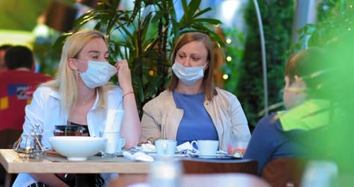 Ladies Take Off Blue Face Masks Sitting at Restaurant Table