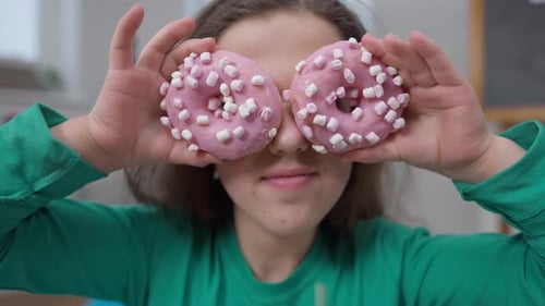 Closeup Joyful Little Person Playing with Sweet Delicious Donuts Showing Tongue Front View