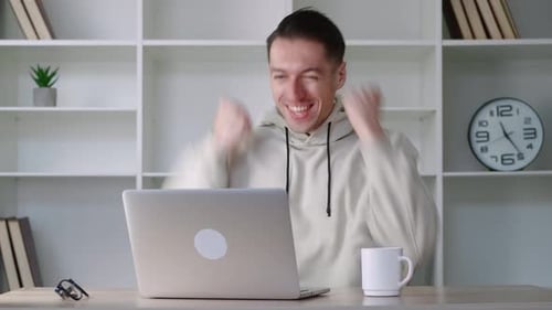 Excited man with laptop celebrating success at home