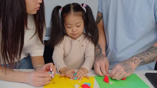 Family Plays with Modeling Clay at Table