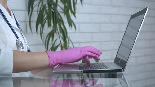 Medical Professional Typing on Laptop with Pink Gloves