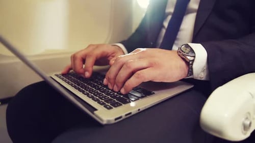 Business Person Typing on Laptop in Airplane