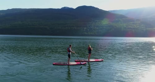 Couple on stand up paddle board oaring in river 4k