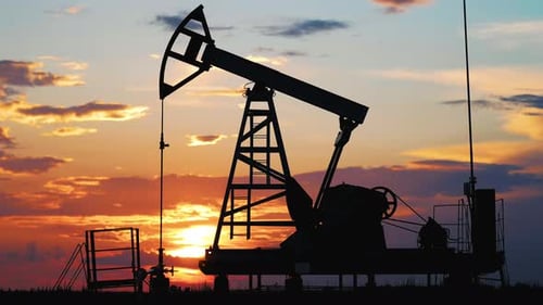 Silhouette Working Oil Pump in Deserted District at Sunset