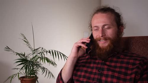 Man with Red Beard Talking on Phone Indoors