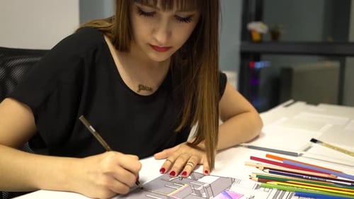 Woman Working on Architectural Drawing at Desk