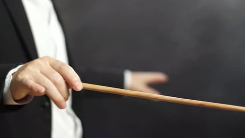 Close Up Side View Of Conductor'S Hands Holding A Baton And Moving In The Black Studio