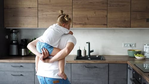 Dad Giving Daughter Piggyback Ride in Kitchen