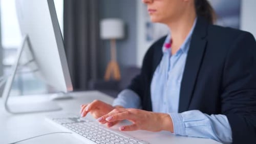 Woman Typing on Computer Keyboard in Office Setting