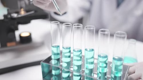 Scientist Adding Liquid to Test Tubes in Laboratory