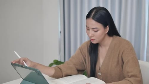 Woman Studying with Tablet and Book Indoors