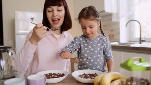 Woman and Child Eating Cereal in Kitchen