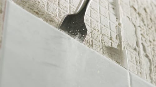 Slow motion of a rotary hammer breaking ceramic tiles off a wall