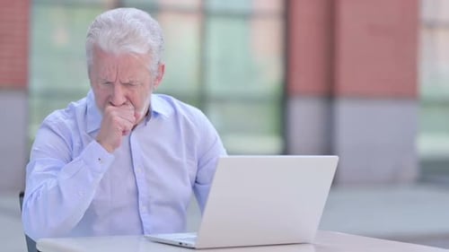 Senior Man Coughing While Using Laptop Outdoors