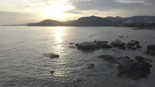 Aerial fly over rock at sea near Penang Island.