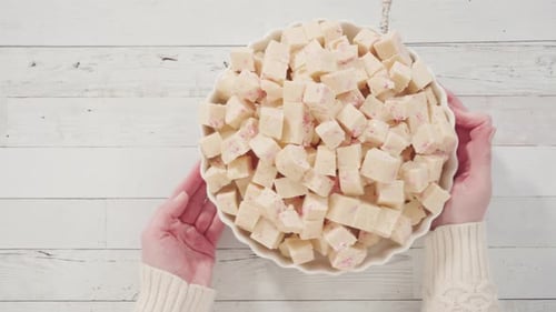 Flat lay. Step by step. Candy cane fudge cut in small cubes on a white serving dish