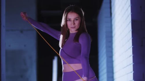 Young Pretty Woman in Sports Suit Playing with a Jumping Rope in the Gym and Looking in the Camera