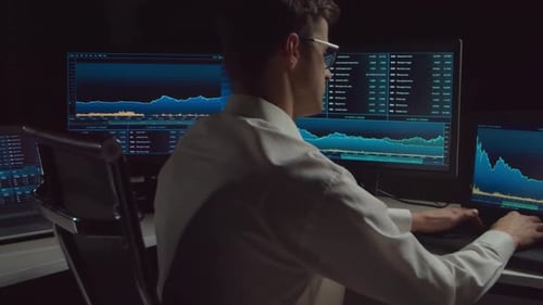 Trader working in office at night using workstation and analysis technology.