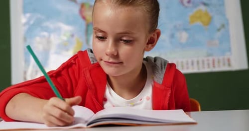 Schoolgirl doing homework in classroom at school