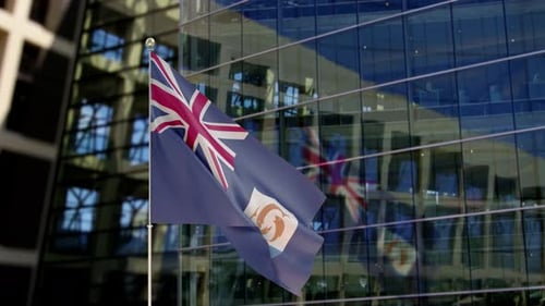 Anguilla Flag Waving in Front of Modern Glass Building