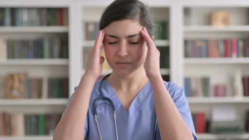 Young Adult Nurse with Headache in Front of Bookshelf