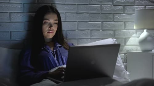Woman Using Laptop in Bed at Night
