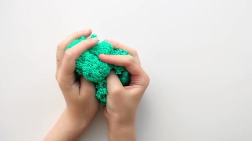 Hands Playing with Textured Slime with Bubbles Stretching the Gooey Substance on White Background