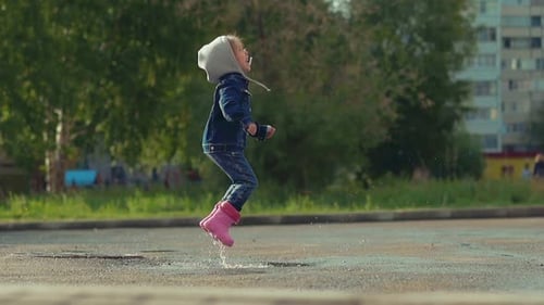 Little Child Happily Jumps in Deep Puddle