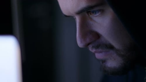 Nahaufnahme eines jungen Hackers, der sich auf das Tippen auf dem Computer konzentriert