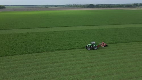 Mowing with a Agriculture Machine Modern Tractor with Mowers on the Big Farm Field