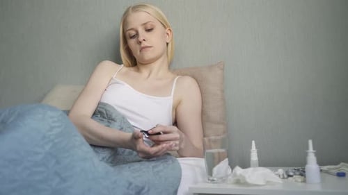 Young Woman Takes Medicine While Lying in Bed