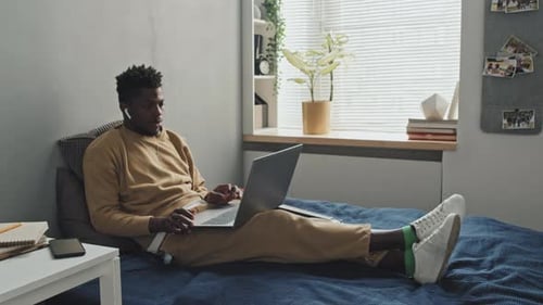 Young Adult Working on Laptop in Bedroom