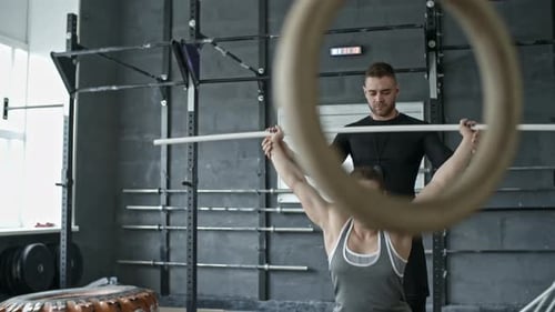 Woman Lifts Barbell With Trainer in Urban Gym