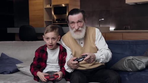 Senior and Child Play Video Games on Couch